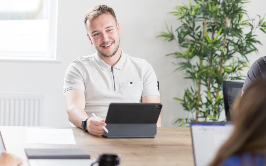 A person at a laptop smiling at someone sitting across from them